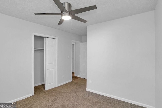 unfurnished bedroom featuring a textured ceiling, a closet, carpet, baseboards, and a ceiling fan