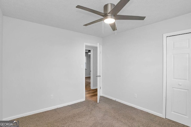 unfurnished bedroom with carpet flooring, a textured ceiling, baseboards, and ceiling fan