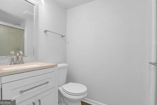 full bath with toilet, a stall shower, vanity, and baseboards