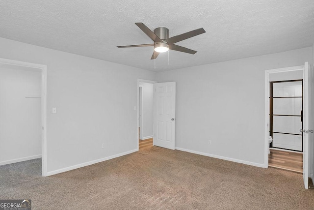 unfurnished bedroom with carpet, baseboards, a textured ceiling, a ceiling fan, and a spacious closet