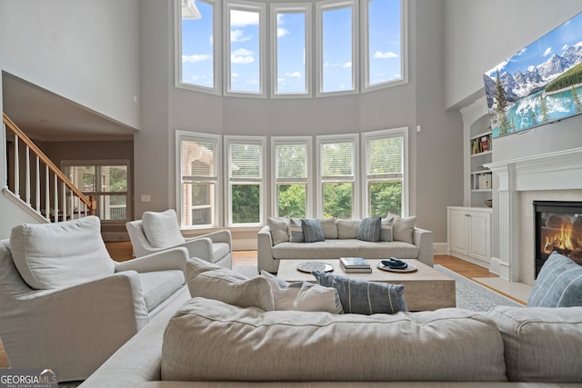 100 Braxton Way, Roswell, GA 30075 - living area featuring a towering ceiling, plenty of natural light, built in features, light wood-type flooring, and a fireplace