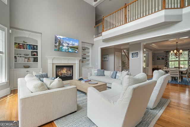 100 Braxton Way, Roswell, GA 30075 - living room featuring a high ceiling, built in shelves, stairs, light wood finished floors, and a chandelier