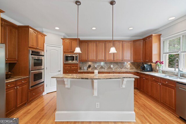 100 Braxton Way, Roswell, GA 30075 - kitchen featuring a sink, appliances with stainless steel finishes, crown molding, a breakfast bar area, and light stone counters