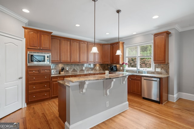 100 Braxton Way, Roswell, GA 30075 - kitchen with appliances with stainless steel finishes, brown cabinets, light stone counters, light wood-style floors, and crown molding