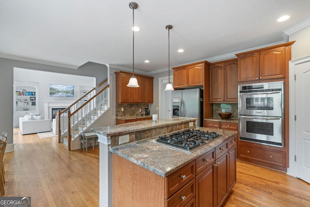 100 Braxton Way, Roswell, GA 30075 - kitchen featuring stainless steel appliances, ornamental molding, a kitchen island, brown cabinets, and light stone counters