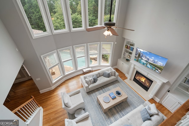 100 Braxton Way, Roswell, GA 30075 - living room featuring a towering ceiling, plenty of natural light, wood finished floors, and a glass covered fireplace