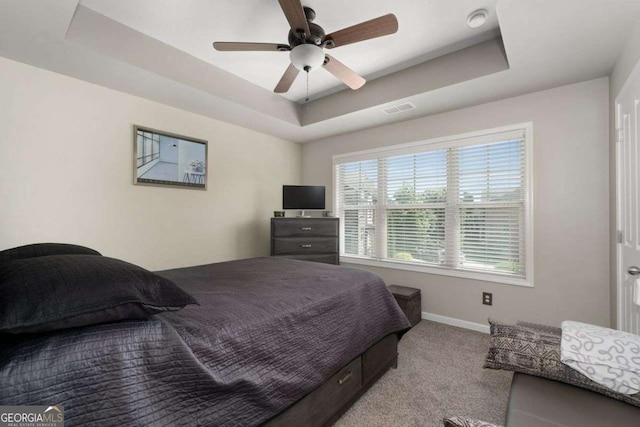 bedroom with a tray ceiling, baseboards, carpet flooring, and a ceiling fan