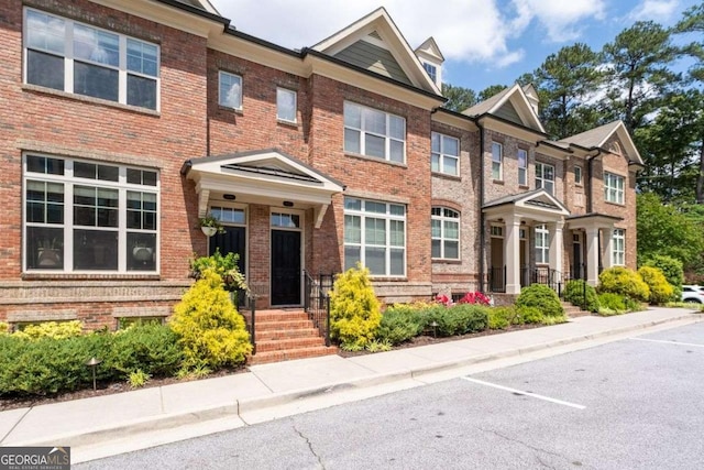 multi unit property featuring brick siding and uncovered parking
