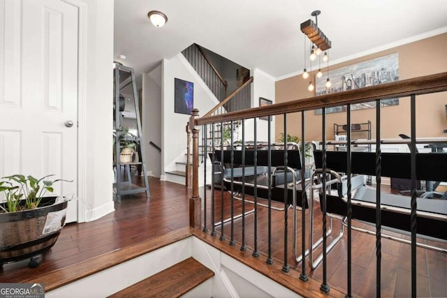 staircase featuring hardwood / wood-style flooring, crown molding, and baseboards