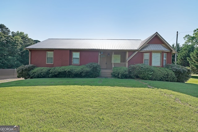 view of front of home featuring a front lawn, covered porch, and metal roof