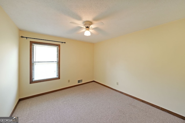carpeted empty room featuring a ceiling fan, baseboards, and a textured ceiling