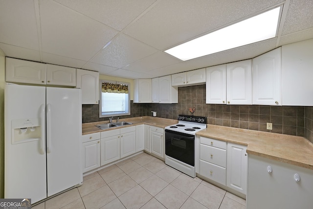 kitchen featuring white appliances, a sink, white cabinets, decorative backsplash, and a paneled ceiling