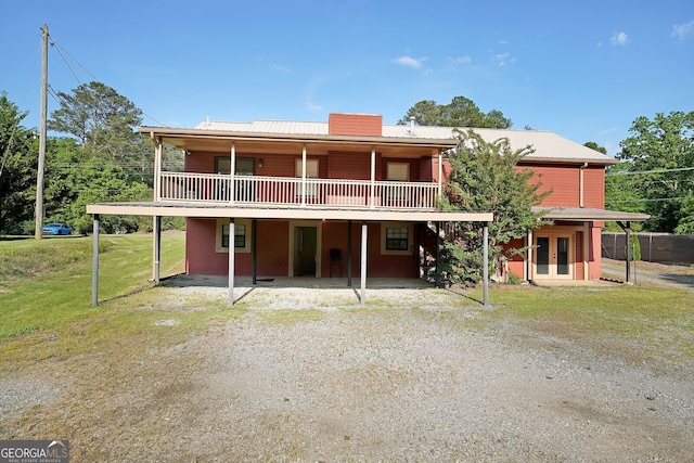 back of house featuring french doors, a wooden deck, dirt driveway, and metal roof