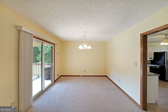 unfurnished dining area featuring a chandelier, light colored carpet, a textured ceiling, baseboards, and ceiling fan