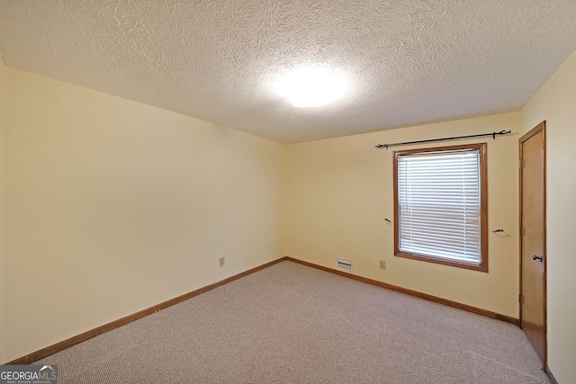 unfurnished room featuring light colored carpet, a textured ceiling, and baseboards