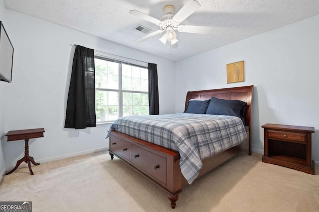 bedroom with light carpet, a textured ceiling, baseboards, and a ceiling fan