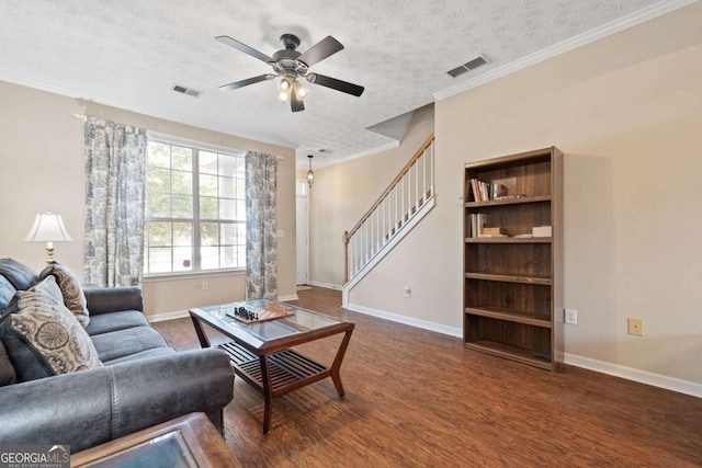 living area with stairway, a ceiling fan, wood finished floors, baseboards, and a textured ceiling