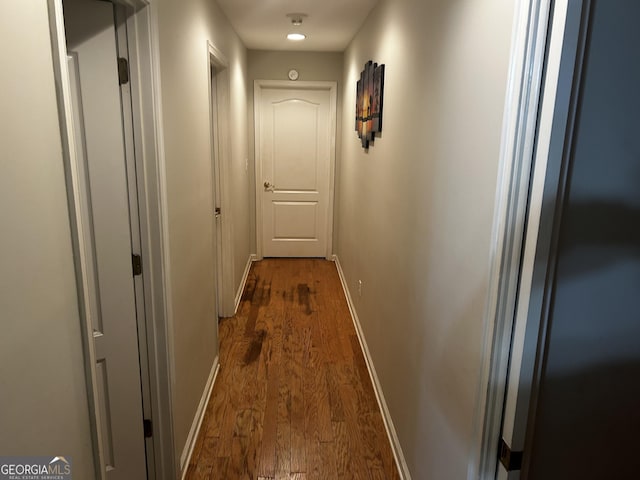 hall featuring dark wood-style flooring and baseboards