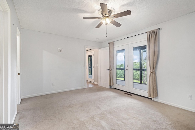 carpeted spare room featuring french doors, a textured ceiling, a ceiling fan, and baseboards