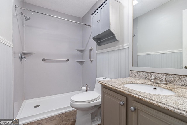 bathroom with a shower, vanity, toilet, and wainscoting