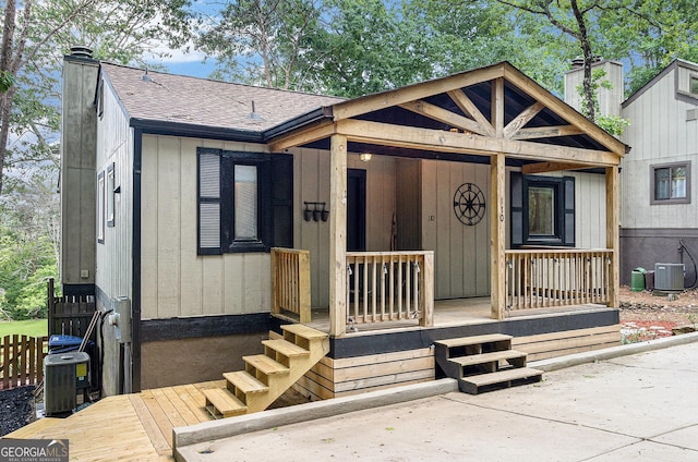 view of front of home featuring a chimney, cooling unit, and a shingled roof