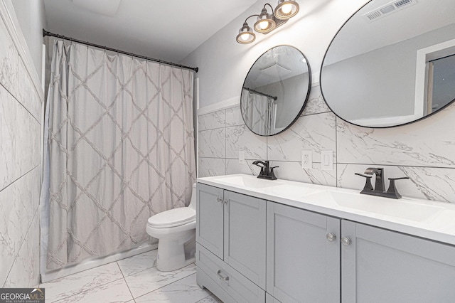 bathroom with marble look tiles, double vanity, toilet, curtained shower, and tile walls