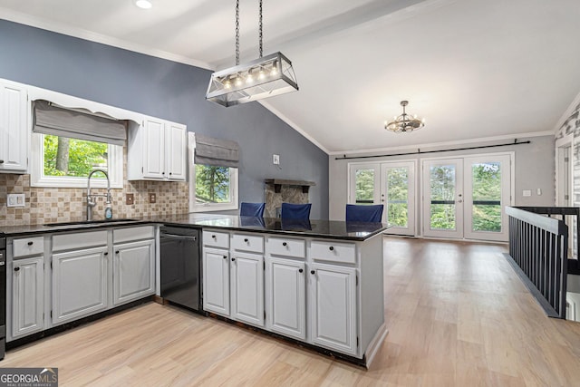 kitchen featuring dishwasher, a peninsula, a sink, vaulted ceiling, and a chandelier