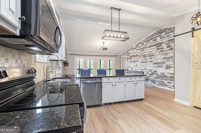 kitchen featuring stainless steel appliances, vaulted ceiling, a barn door, a sink, and light wood-style flooring