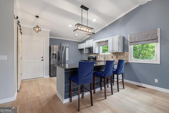 kitchen featuring stainless steel appliances, a peninsula, lofted ceiling, a breakfast bar area, and ornamental molding