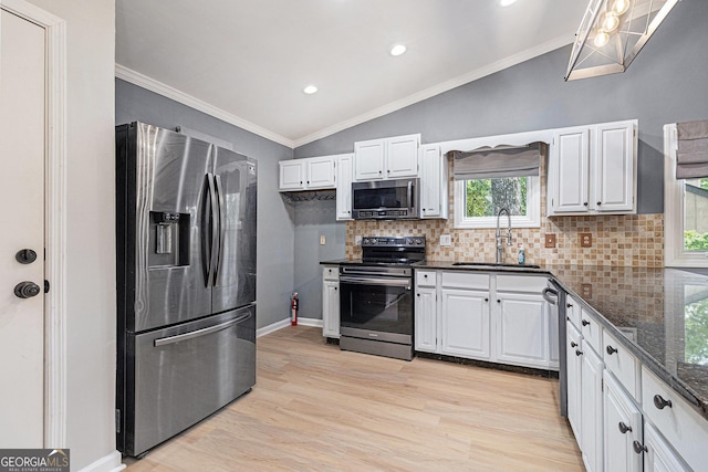 kitchen with appliances with stainless steel finishes, a sink, lofted ceiling, backsplash, and light wood-style floors