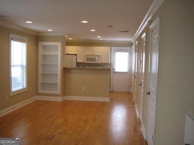 unfurnished living room featuring ornamental molding, light wood-type flooring, recessed lighting, and baseboards
