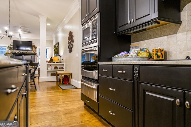 kitchen with crown molding, a warming drawer, appliances with stainless steel finishes, light wood-type flooring, and decorative backsplash