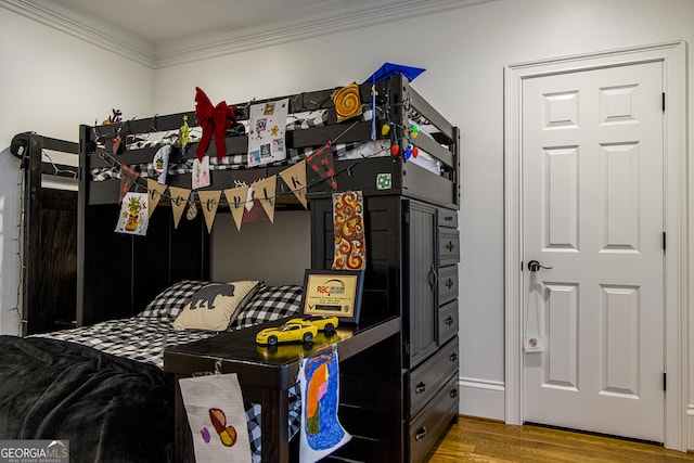 bedroom with ornamental molding and wood finished floors