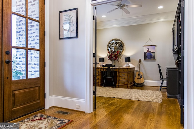foyer entrance featuring baseboards, ornamental molding, dark wood finished floors, and a ceiling fan