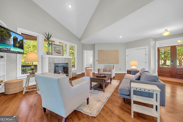 living area with a tiled fireplace, wood finished floors, vaulted ceiling, recessed lighting, and baseboards