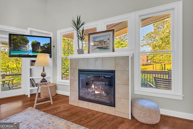 detailed view of a fireplace, wood finished floors, and baseboards