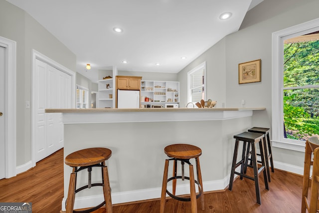 kitchen featuring freestanding refrigerator, a kitchen breakfast bar, wood finished floors, open shelves, and recessed lighting