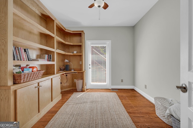 doorway featuring a ceiling fan, wood finished floors, and baseboards