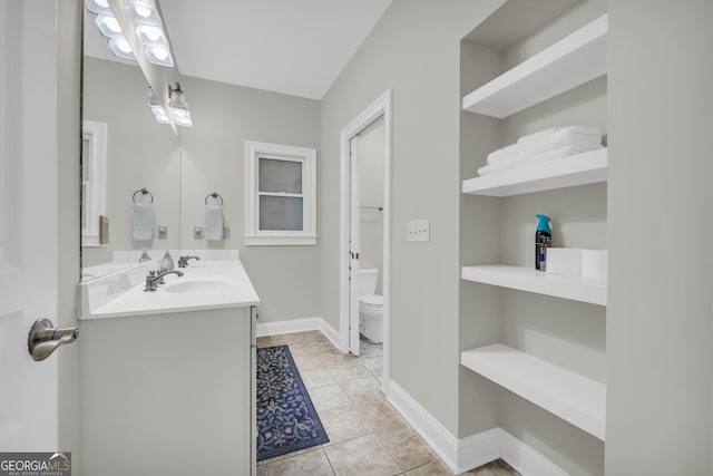 full bathroom with toilet, double vanity, baseboards, and tile patterned flooring