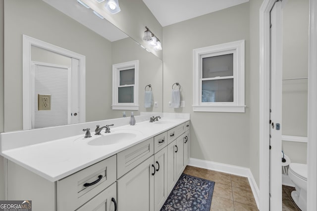 full bath featuring double vanity, toilet, baseboards, and tile patterned floors