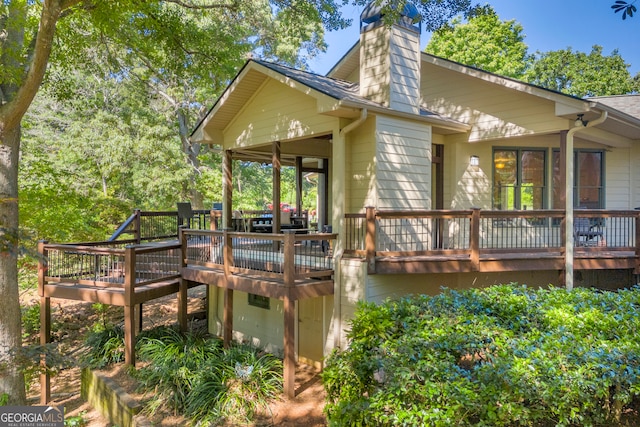 rear view of house featuring a deck and a chimney