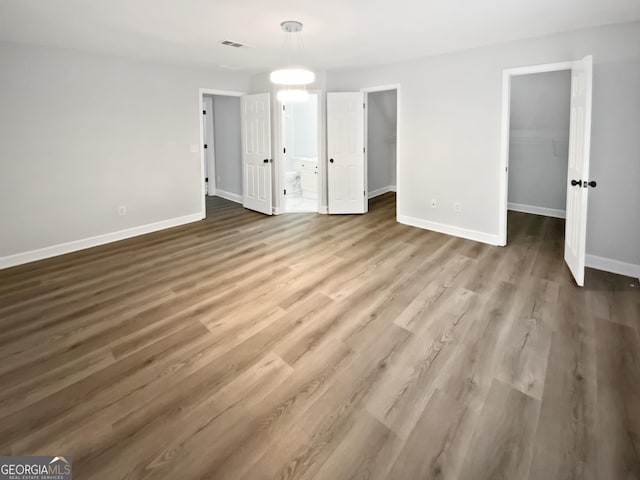 4345 Park Brooke Trce, Johns Creek, GA 30022 - unfurnished bedroom featuring a walk in closet, wood finished floors, a closet, and ensuite bathroom