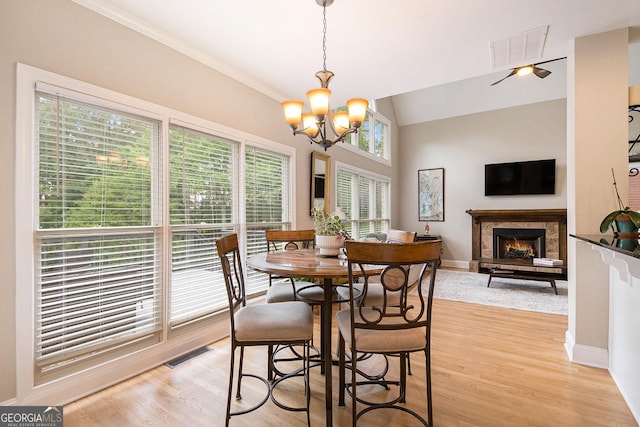 1640 Settindown Dr, Roswell, GA 30075 - dining area with a warm lit fireplace, a chandelier, light wood-style flooring, baseboards, and crown molding