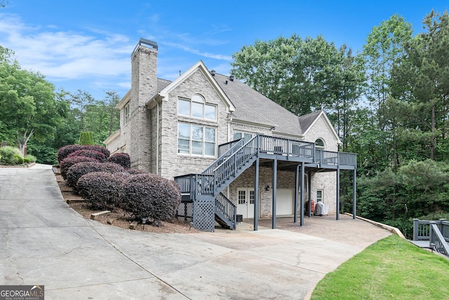 1640 Settindown Dr, Roswell, GA 30075 - view of front facade with stairs, concrete driveway, a wooden deck, a chimney, and stone siding