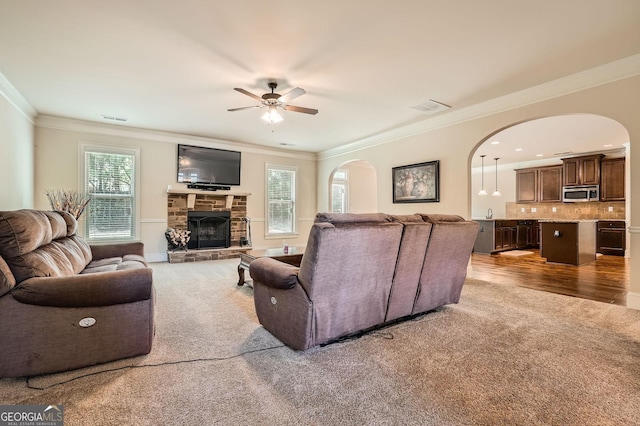 349 Pennant Ln, Fairburn, GA 30213 - living area with arched walkways, ornamental molding, healthy amount of natural light, a stone fireplace, and ceiling fan