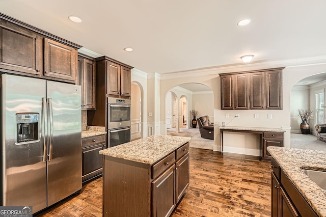 349 Pennant Ln, Fairburn, GA 30213 - kitchen with appliances with stainless steel finishes, arched walkways, crown molding, dark brown cabinetry, and open floor plan
