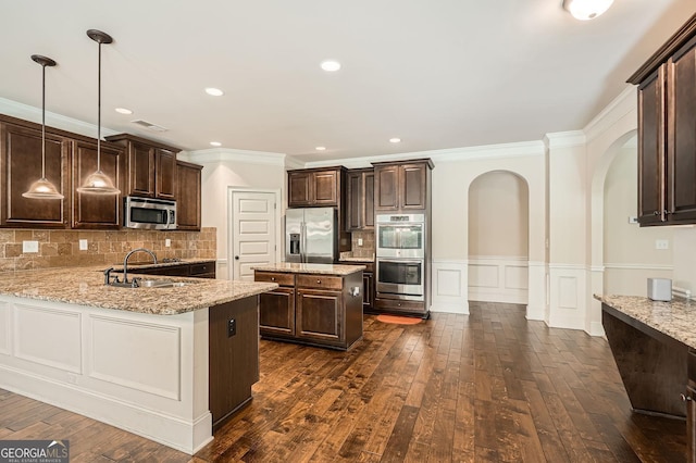 349 Pennant Ln, Fairburn, GA 30213 - kitchen with stainless steel appliances, arched walkways, dark brown cabinets, ornamental molding, and light stone counters