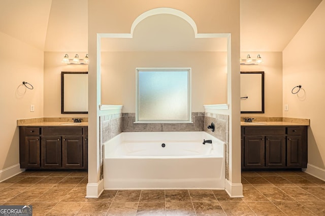 349 Pennant Ln, Fairburn, GA 30213 - bathroom with a garden tub, baseboards, two vanities, and vaulted ceiling