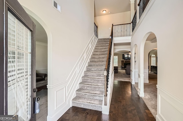 349 Pennant Ln, Fairburn, GA 30213 - foyer with arched walkways, dark wood-style flooring, stairs, a high ceiling, and wainscoting