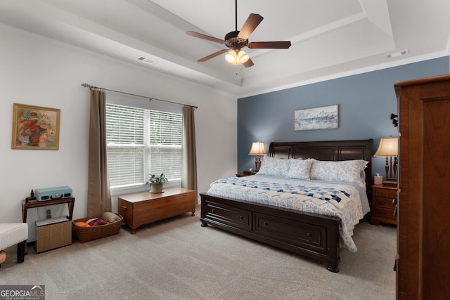 bedroom featuring a tray ceiling, light colored carpet, and ceiling fan